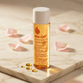 Bio-Oil 125 ml — packshot premium em mármore creme com pétalas de rosa